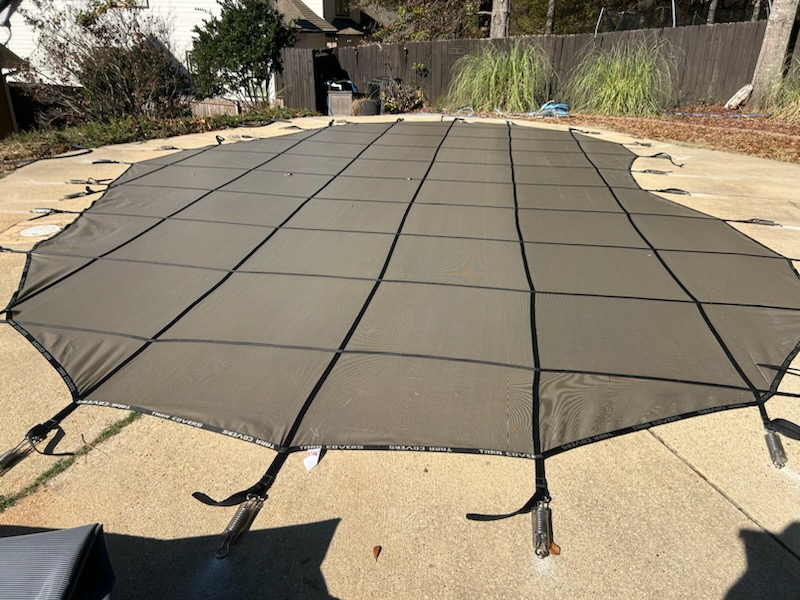 Close-up of anchored pool safety cover straps on patio deck