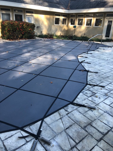 Dark blue pool safety cover installed at residential property